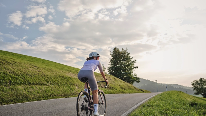 Rennradlerin fährt auf Straße Richtung Horizont