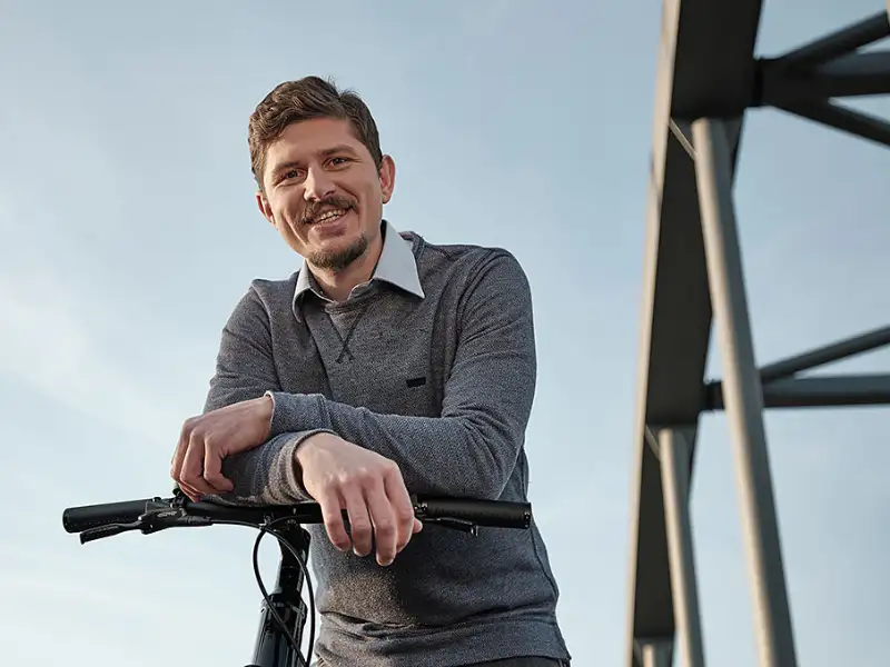 Mann auf Brücke lehnt über Lenker