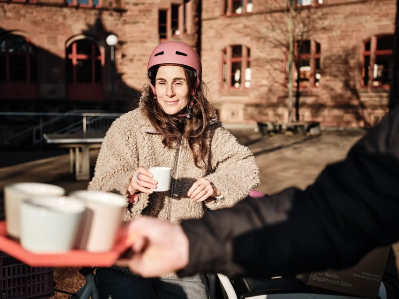 Junge Frau mit Fahrradhelm und Coffee-to-go